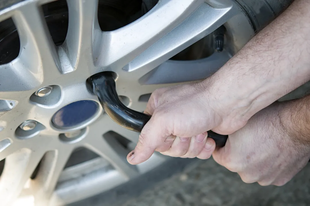 imagen de como cambiar una rueda de coche con llave quitando tuercas